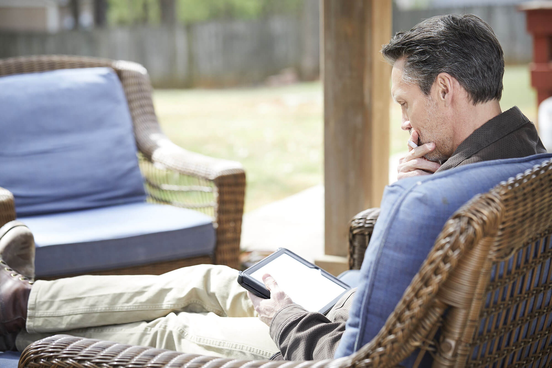 man sitting on couch, holding tablet device